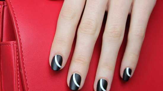 Lunares blancos sobre base negra en uñas cortas.