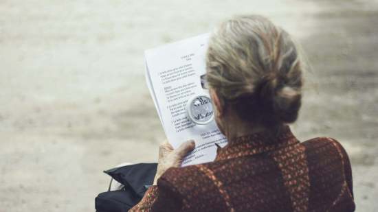 señora con lupa leyendo un texto en papel
