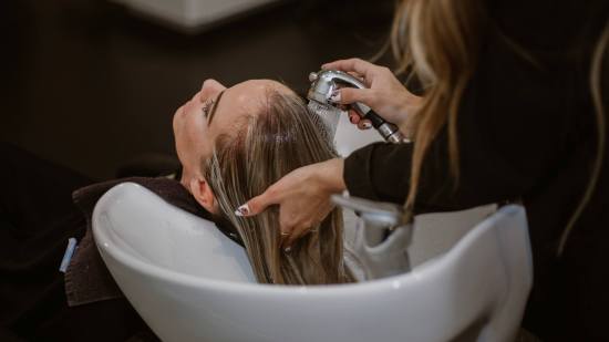 mujer rubia en la peluqueria mientras le lavan la cabeza