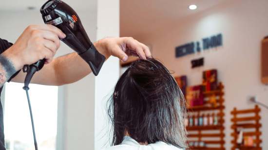 peluquero secando el pelo a una mujer con secador