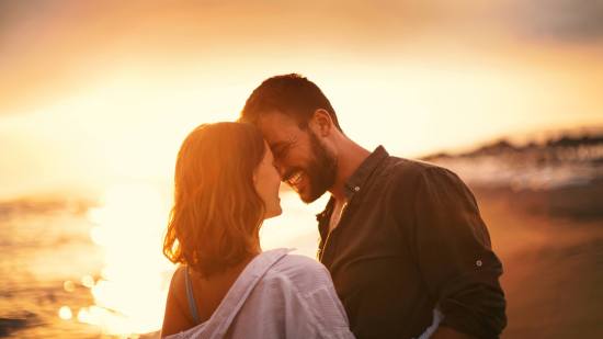 pareja enamorada mirandose sonriendo en la playa
