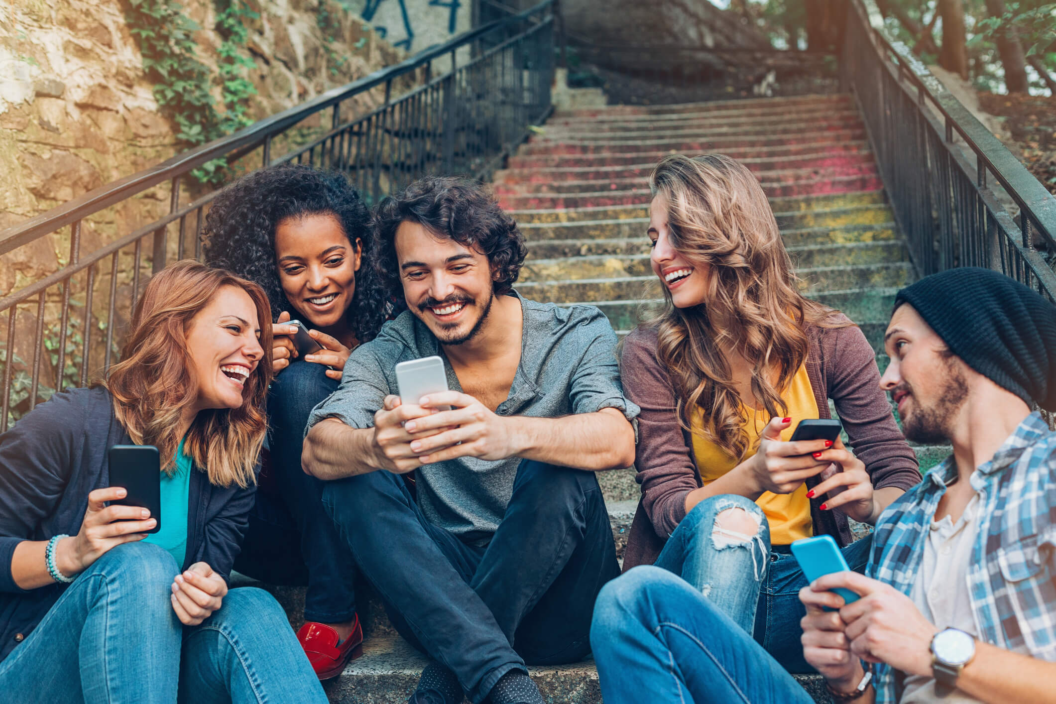 grupo de cinco amigos mirando sus telefonos moviles