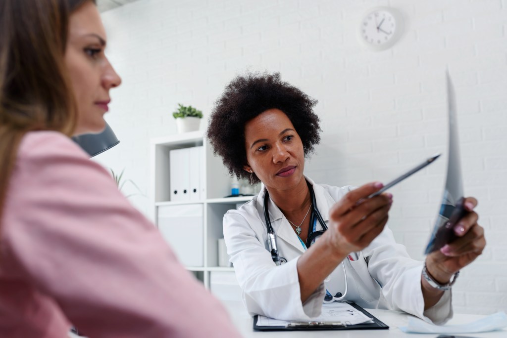 Doctora leyéndole los resultados a su paciente - iStock