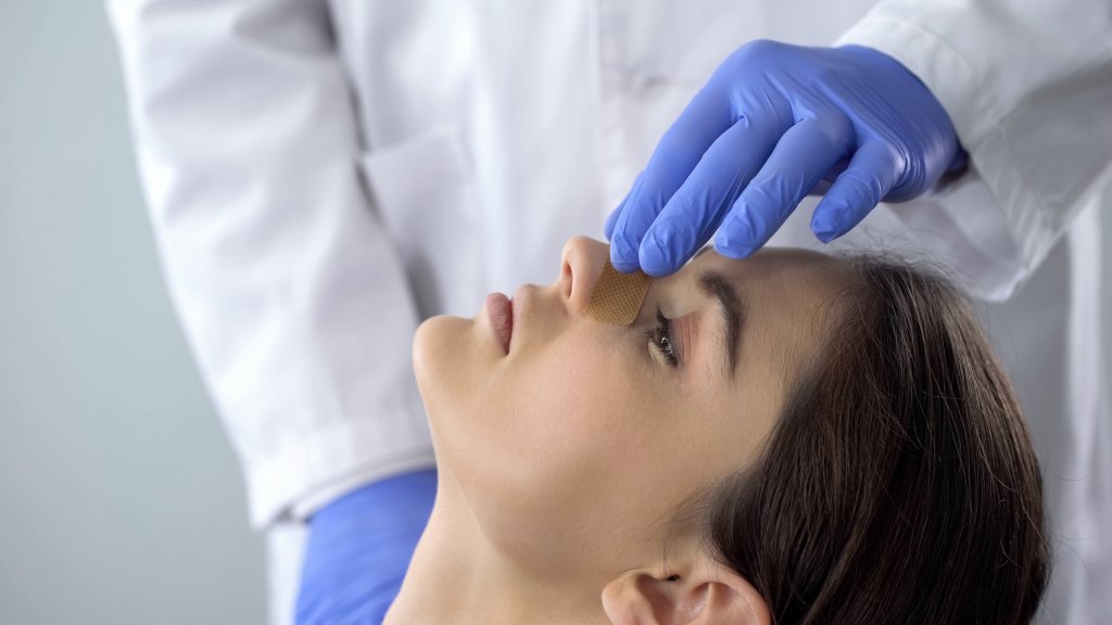 Doctor examinando a su paciente después de una cirugía nasal - Imagen: iStock