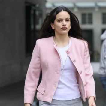 La cantante Rosalía paseando por Londres con un look con chaqueta rosa, rosario y botas moteras